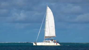 Havadan çekilen görüntüler, açık mavi denizde seyreden lüks yelkenli görüntüsü. Kamera mavi okyanus suyunda katamaranı takip ediyor. Yüksek kalite 4k görüntü