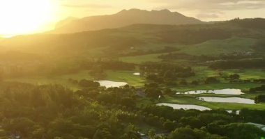 Golf oteli kıyısı Hint Okyanusu. Sahilde golf sahası ve villalar. Golf sahasının havadan görüntüsü. Atış yapmak, golf kulübünün üzerinde uçmak. Yaz zamanı, gün batımı. Zengin insanların hayatı. Mauritius.