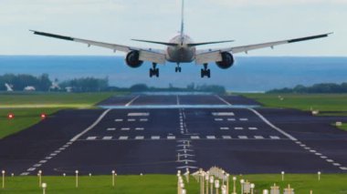 İniş için sahile giden yolcu uçağı, hava görüntüsü. Beyaz tanımlanamayan ticari jet uçağı, iniş takımları açık, arka plan okyanus. Yüksek kalite 4k görüntü