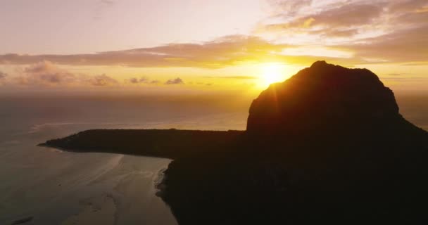 モーン山の後ろに昇る太陽の風景空撮 モーリシャスの夕日の美しい景色とビーチや岩が前景に見える山 高品質4K映像 — ストック動画