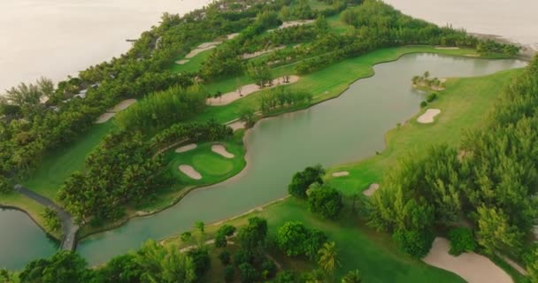 鸟瞰高尔夫球场 绿草绿树林立 夏日阳光灿烂 鸟瞰高尔夫球场 令人惊奇 海滩上的绿地和别墅 高质量的4K镜头 — 图库视频影像