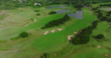 Yeşil çimen ve ağaçlarla birlikte golf sahasının havadan görünüşü. Güneşli yaz günlerinde golf sahalarında kuşbakışı inanılmaz bir manzara. Sahilde yeşil saha ve villalar. Yüksek kalite 4k görüntü