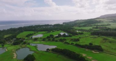 Yeşil çimen ve ağaçlarla birlikte golf sahasının havadan görünüşü. Güneşli yaz günlerinde golf sahalarında kuşbakışı inanılmaz bir manzara. Sahilde yeşil saha ve villalar. Yüksek kalite 4k görüntü