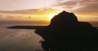 Hint Okyanusu 'ndaki güzel dağın havadan görünüşü. Gün batımının son ışınları dağın zirvesine vurdu. Dağdan okyanusa, gün batımından panorama. Yüksek kalite 4k görüntü
