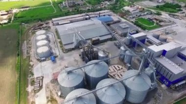 Buğday tarlasının yakınındaki hava manzaralı tahıl, buğday ve soya fasulyesi depolama asansörleri. Tarım. Tahıl, soya fasulyesi ve buğday işlemek ve depolamak için konteynırlar. Yüksek kaliteli FullHD görüntüler