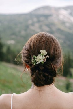 Saçında beyaz çiçekler olan gelinin düğün saç stili.