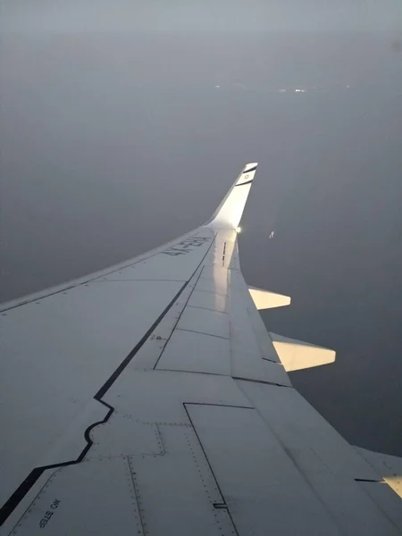 Aile d'avion dans le ciel gris, volant au coucher du soleil — Photo