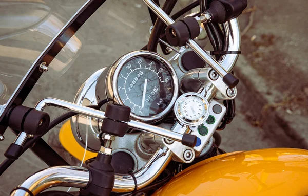 Motorcycle speedometer and dashboard with wind glass. Shiny, custom, stylish, yellow motorbike panel fragment close up. Retro design transportation. Freedom, speed and vehicle repair workshop concept