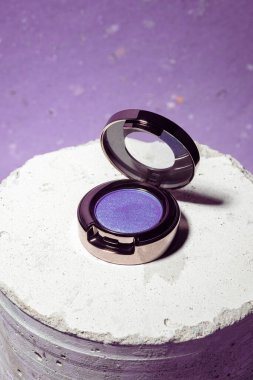 Purple eyeshadow pot on bright background. Beauty makeup product on display. Bright sparkles, shimmer, metallic, solid color shadow. Make-up artist tool. Summer or autumn shade. Macro shot, copy space