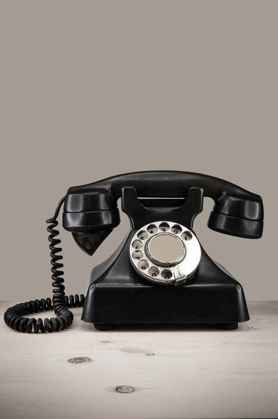 Old vintage phone with rotary disc on wooden table grunge background