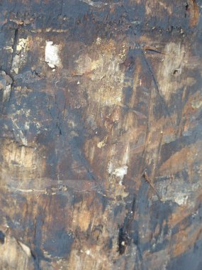 Yakıt yağına bulanmış kirli bir tahta direğin yüzeyi yırtık reklamlarla dolu.