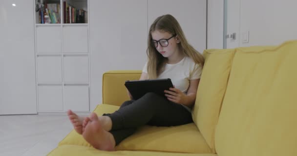 Barefoot Meisje Bril Zitten Bank Kijken Naar Video Tablet Tijdens — Stockvideo