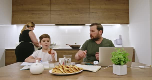 Vousatý Otec Pomocí Notebooku Práce Pomáhá Snacking Syn Domácím Úkolem — Stock video