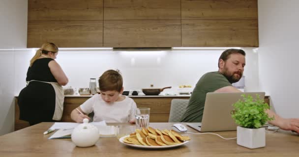 Poika Tekee Läksyjä Mies Käyttää Kannettavaa Etätyöhön Istuessaan Keittiön Pöydässä — kuvapankkivideo
