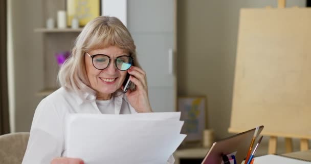 在家里工作的老女人经常在电话里与同事讨论工作的过程时面带微笑 — 图库视频影像