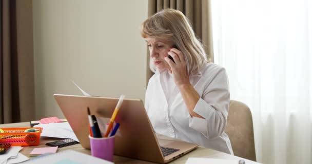 在Covid 19大流行期间 一位在家里工作的老年妇女坐在笔记本电脑前 与一位客户或同事讨论文书工作 — 图库视频影像