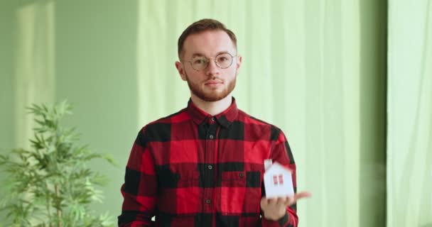 Hombre Joven Positivo Camisa Cuadros Gafas Que Demuestran Pequeña Casa — Vídeos de Stock