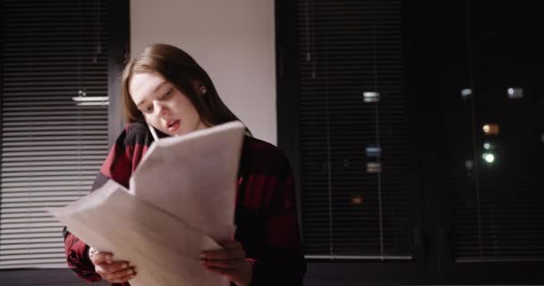 若い女性社員がオフィスで仕事をしながらビジネス上の問題や書類の裏返しについて話し合う — ストック動画