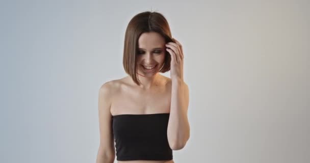 カメラの笑顔でポーズをとった短い散髪のモデル少女が幸せ ホワイトスタジオの背景 高品質4K映像 — ストック動画