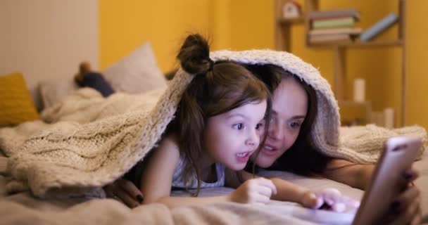 Mujer Niña Acostadas Bajo Una Manta Punto Viendo Video Celular — Vídeo de stock