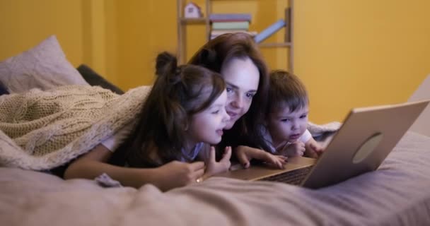 Donna Bambini Sdraiati Sul Letto Sotto Coperta Guardando Film Netbook — Video Stock