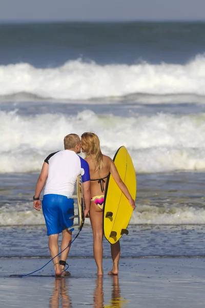 Серфингисты целуются на пляже — стоковое фото