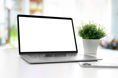 Laptop with blank screen on table in bright livingroom - home office background