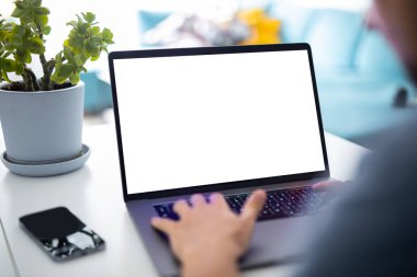 Ev içinde boş ekranlı dizüstü bilgisayar kullanan bir adam