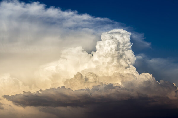 Dramatic cumulonimbus in sun light contrasting with lower dark clouds