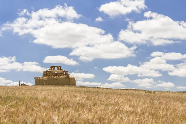 Arruinado palomar de adobe entre un campo de cereales y un bl nublado Fotos De Stock