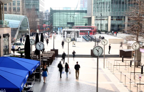 LONDON, UK - MARCH 10, 2014: Canary Wharf square with clocks and office people walking by. Canary Wharf place to work for more than 100 00 people — Stock Photo, Image