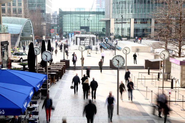 LONDON, UK - MARCH 10, 2014: Canary Wharf square with clocks and office people walking by. Canary Wharf place to work for more than 100 00 people — Stock Photo, Image