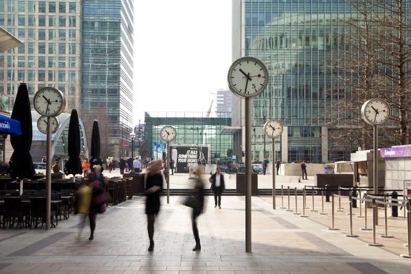 LONDON, UK - MARCH 10, 2014: Canary Wharf square with clocks and office people walking by. Canary Wharf place to work for more than 100 00 people — Stock Photo, Image