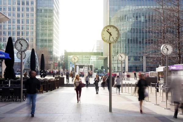 LONDON, UK - MARCH 10, 2014: Canary Wharf square with clocks and office people walking by. Canary Wharf place to work for more than 100 00 people — Stock Photo, Image