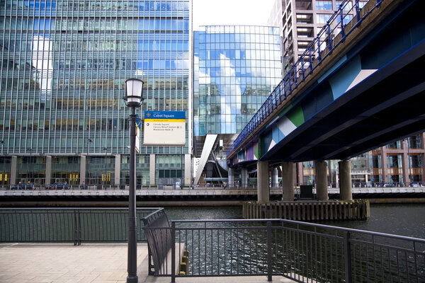 ONDON, CANARY WHARF UK - APRIL 13, 2014 - DLR bridge with train Modern glass architecture of Canary Wharf business aria, headquarters for banks, insurance, media and other world known companies