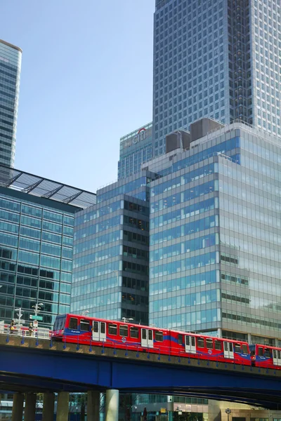 LONDON, CANARY WHARF UK - APRIL 13, 2014 - DLR bridge with train Modern glass architecture of Canary Wharf business aria, headquarters for banks, insurance, media and other world known companies — Stock Photo, Image