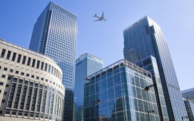 LONDON, UK - JUNE 30, 2014: Aircraft over the London's skyscrapers going to land in the City airport clipart