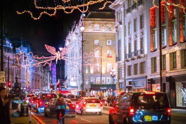 Londra İngiltere - 18 Kasım 2021: Piccadilly Caddesi 'nde festival dekorasyonları ve Noel ışıkları. Bir sürü araba ve karşıdan karşıya geçen insanlar.