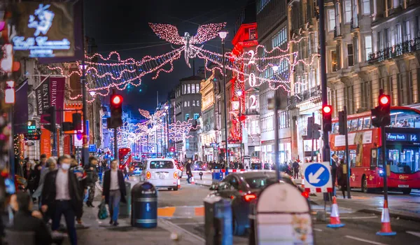 Londra İngiltere - 18 Kasım 2021: Piccadilly Caddesi 'nde festival dekorasyonları ve Noel ışıkları. Bir sürü araba ve karşıdan karşıya geçen insanlar.