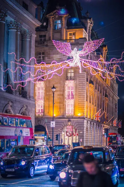 Londra İngiltere - 18 Kasım 2021: Piccadilly Caddesi 'nde festival dekorasyonları ve Noel ışıkları. Ritz Oteli ve yürüyen insanlar.