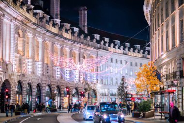 Londra İngiltere - 18 Kasım 2021: Regent Caddesi 'nde festival dekorasyonları ve Noel ışıkları, arabalar, otobüsler ve sokakta yürüyen insanlar