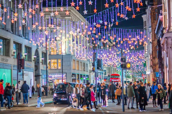 Londra İngiltere - 18 Kasım 2021: Londra, Oxford Caddesi 'nin gece hayatı. Londra 'da Noel süslemeleri ve Noel ışıkları. Sokakta bir sürü insan yürüyor. 