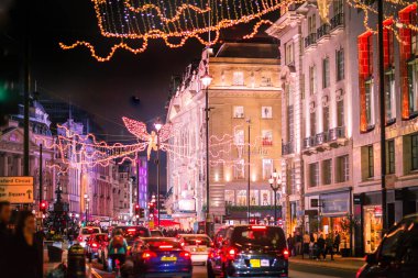 Londra İngiltere - 18 Kasım 2021: Piccadilly Caddesi 'nde festival dekorasyonları ve Noel ışıkları. Bir sürü araba ve karşıdan karşıya geçen insanlar.