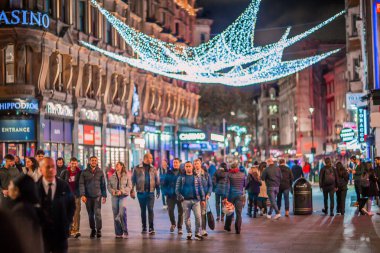 Londra İngiltere - 18 Kasım 2021: Leicester Meydanı 'nda festival dekorasyonları ve Noel ışıkları ve sokakta yürüyen insanlar. Londra 'nın gece hayatı