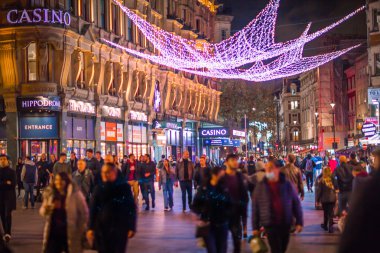 Londra İngiltere - 18 Kasım 2021: Leicester Meydanı 'nda festival dekorasyonları ve Noel ışıkları ve sokakta yürüyen insanlar. Londra 'nın gece hayatı