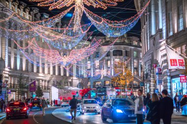 Londra İngiltere - 18 Kasım 2021: Regent caddesinde şenlik dekorasyonları ve Noel ışıkları, arabalar, otobüsler ve sokakta yürüyen insanlar. Londra 'nın gece hayatı 