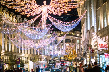Londra İngiltere - 18 Kasım 2021: Regent caddesinde şenlik dekorasyonları ve Noel ışıkları, arabalar, otobüsler ve sokakta yürüyen insanlar. Londra 'nın gece hayatı 