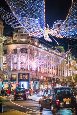 Londra İngiltere - 18 Kasım 2021: Regent caddesinde şenlik dekorasyonları ve Noel ışıkları, arabalar, otobüsler ve sokakta yürüyen insanlar. Londra 'nın gece hayatı 