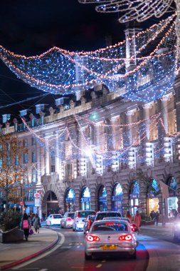Londra İngiltere - 18 Kasım 2021: Regent caddesinde şenlik dekorasyonları ve Noel ışıkları, arabalar, otobüsler ve sokakta yürüyen insanlar. Londra 'nın gece hayatı 