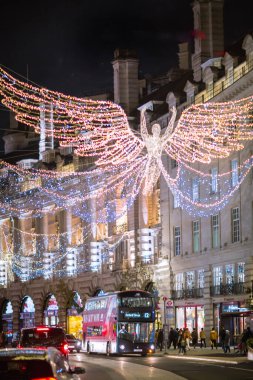 Londra İngiltere - 18 Kasım 2021: Regent caddesinde şenlik dekorasyonları ve Noel ışıkları, arabalar, otobüsler ve sokakta yürüyen insanlar. Londra 'nın gece hayatı 